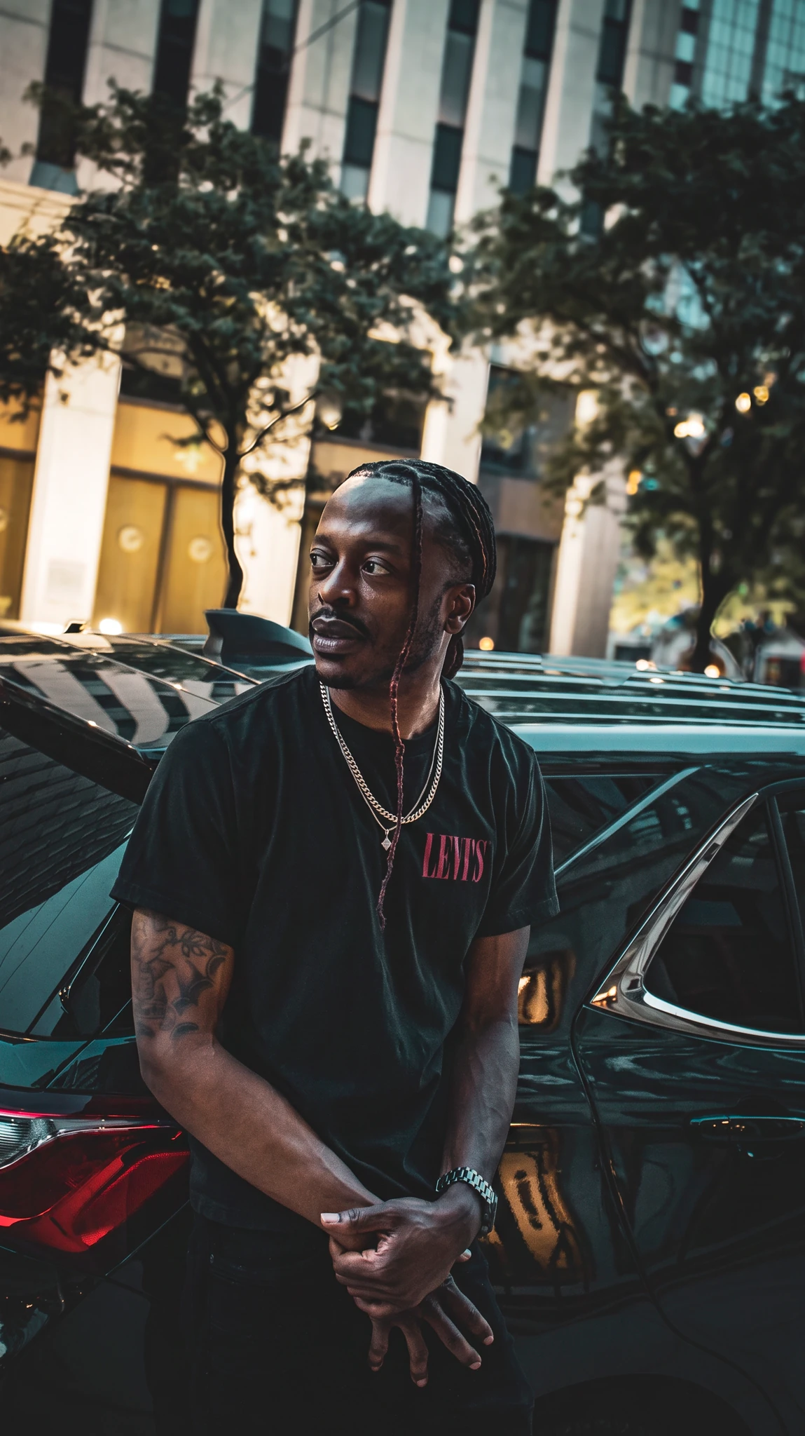Rodney Phimp in a black shirt beside a car outside a glass-fronted building